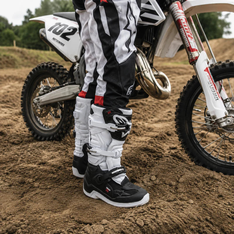 Alpinestars Tech 7s crosslaarzen gedragen door een kind met een KTM crossmotor op de achtergrond.