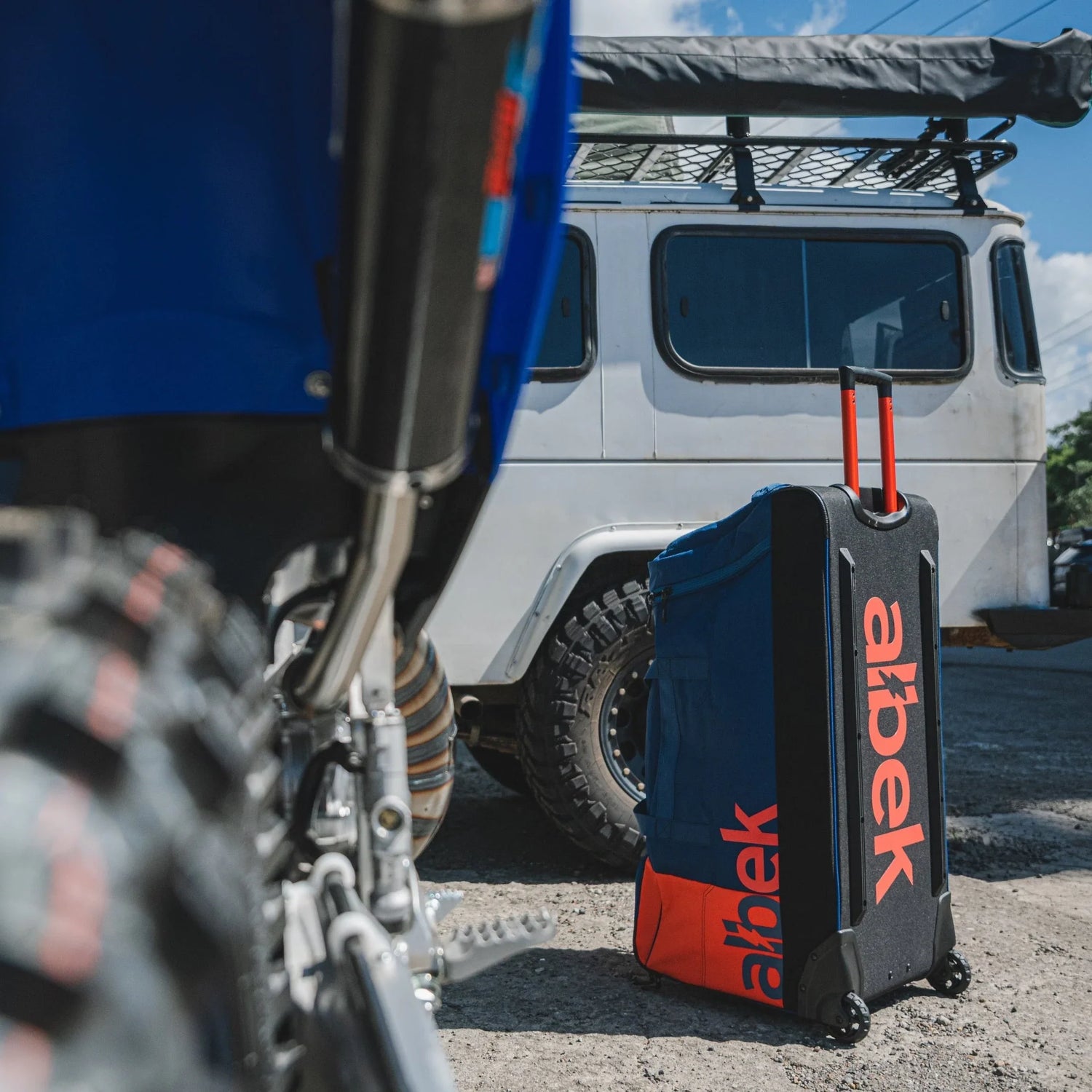 De Albek crosstas in gebruik met op de achtergrond een Yamaha YZ crossmotor en een 4x4 auto.