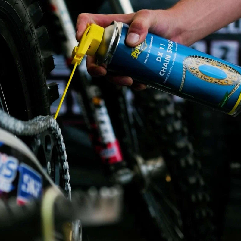 Iemand gebruikt de Putoline DX11 kettingspray op een motorcross ketting.