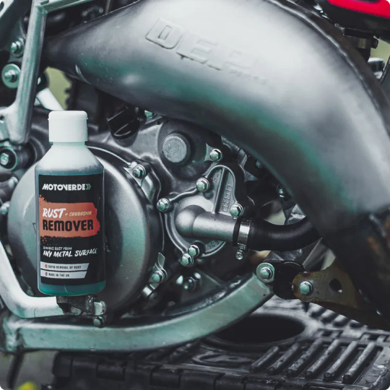 Fles roestverwijderaar die net gebruikt is op de uitlaatbocht van een Yamaha YZ crossmotor.