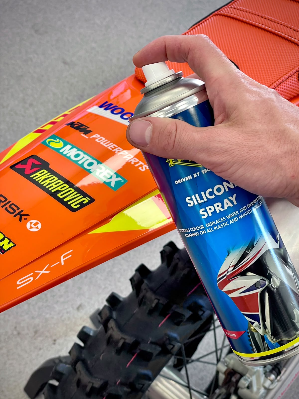 Iemand gebruikt de Putoline Silicone spray om zijn crossmotor weer te laten glimmen.
