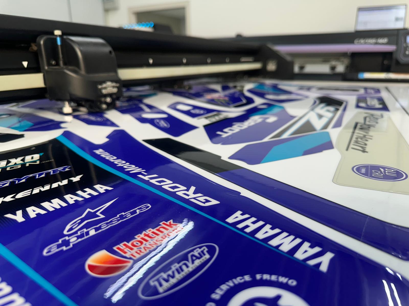 De grote printer is bezig met het printen van de hoge kwaliteit motorcross stickers. Deze worden volledig in eigen ontwerp geproduceerd. Het afgebeelde set is voor een Yamaha.