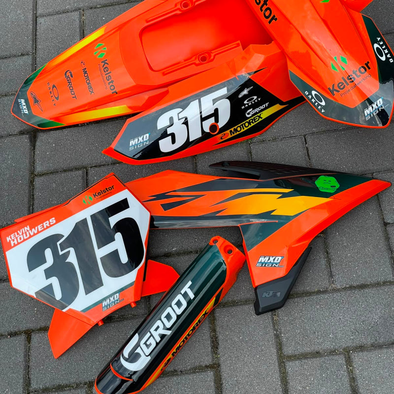 Een volledig custom made stickerset voor een KTM SX85 dat meteen is geplakt op los plastic. De geplakte plastic kappen liggen in een nette opstelling gepresenteerd.
