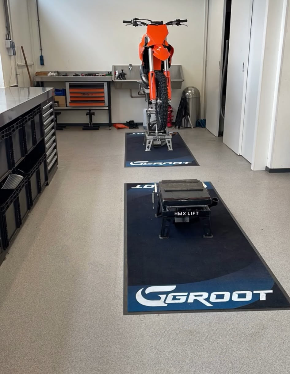 In de professionele werkplaats van Groot motoren liggen hun eigen ontworpen pitmatten van hoge kwaliteit. Hierop staan de schaarliften voor motoren met een KTM SX 125 erop.