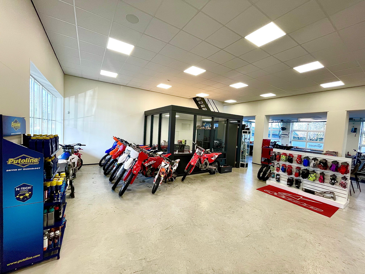 Ruime en goed verlichte showroom met motoren en een open werkplaats.